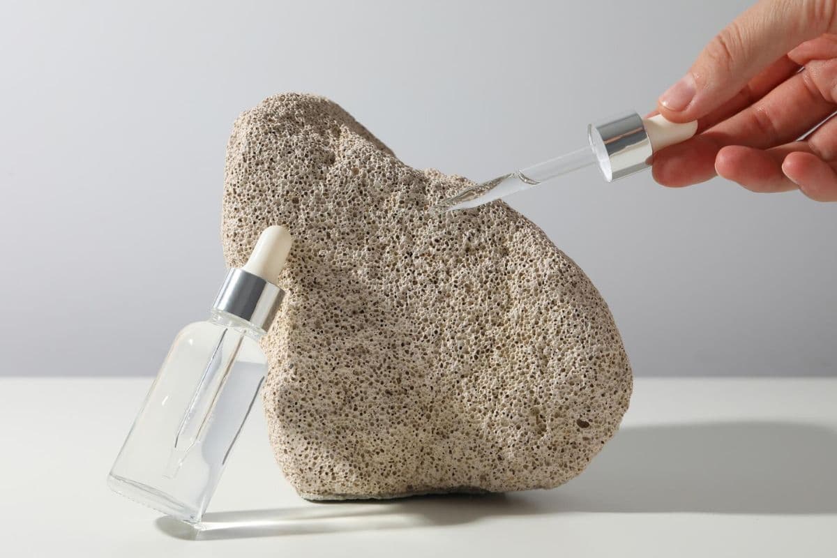 Botol kosmetik dan pipetnya di dekat batu