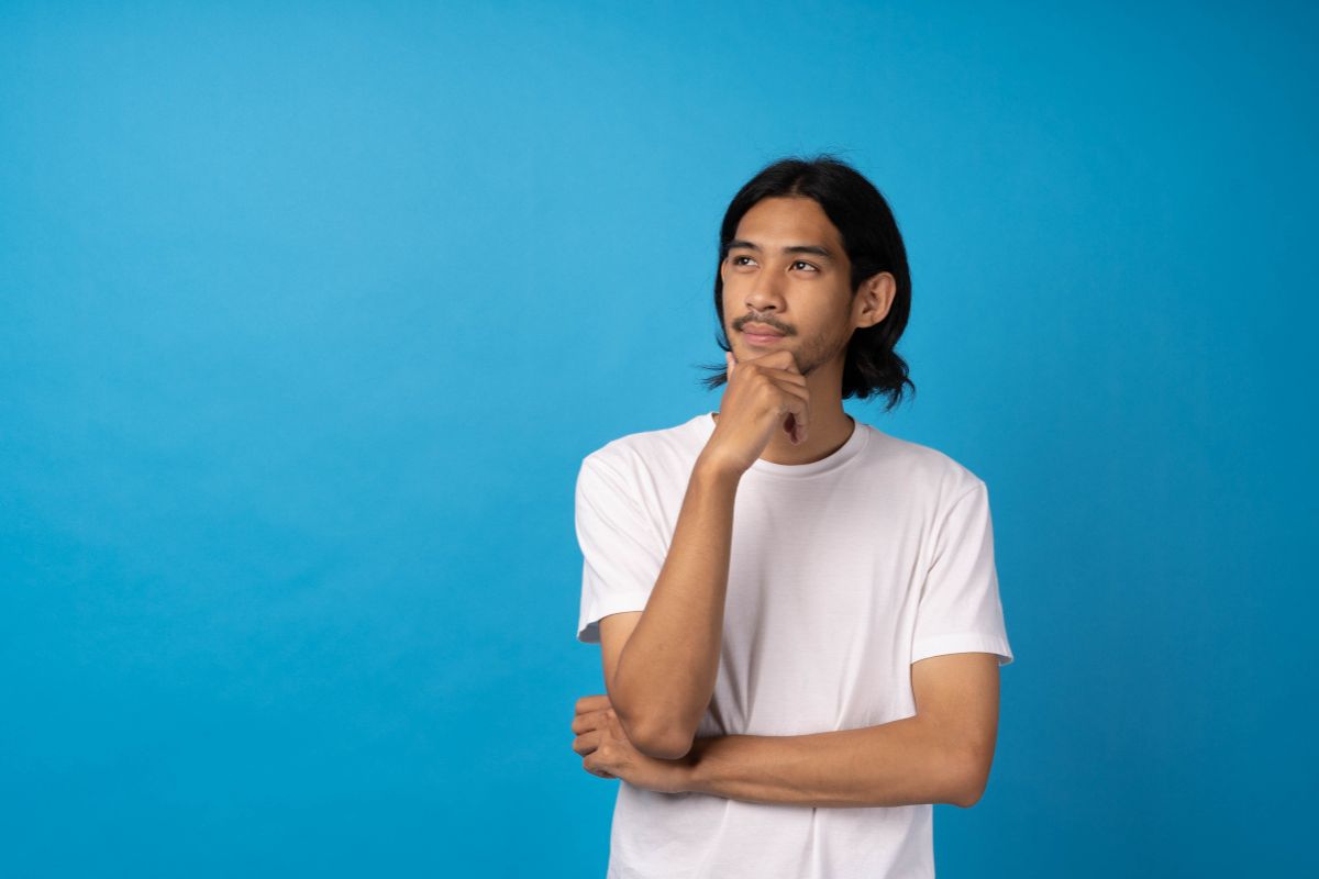 pria berbaju putih berpose dengan backgroung berwarna biru
