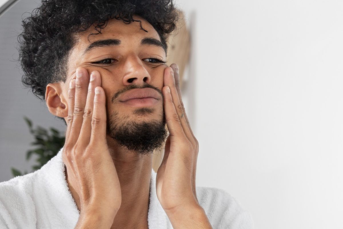 pria sedang menyentuh wajah di hadapan cermin