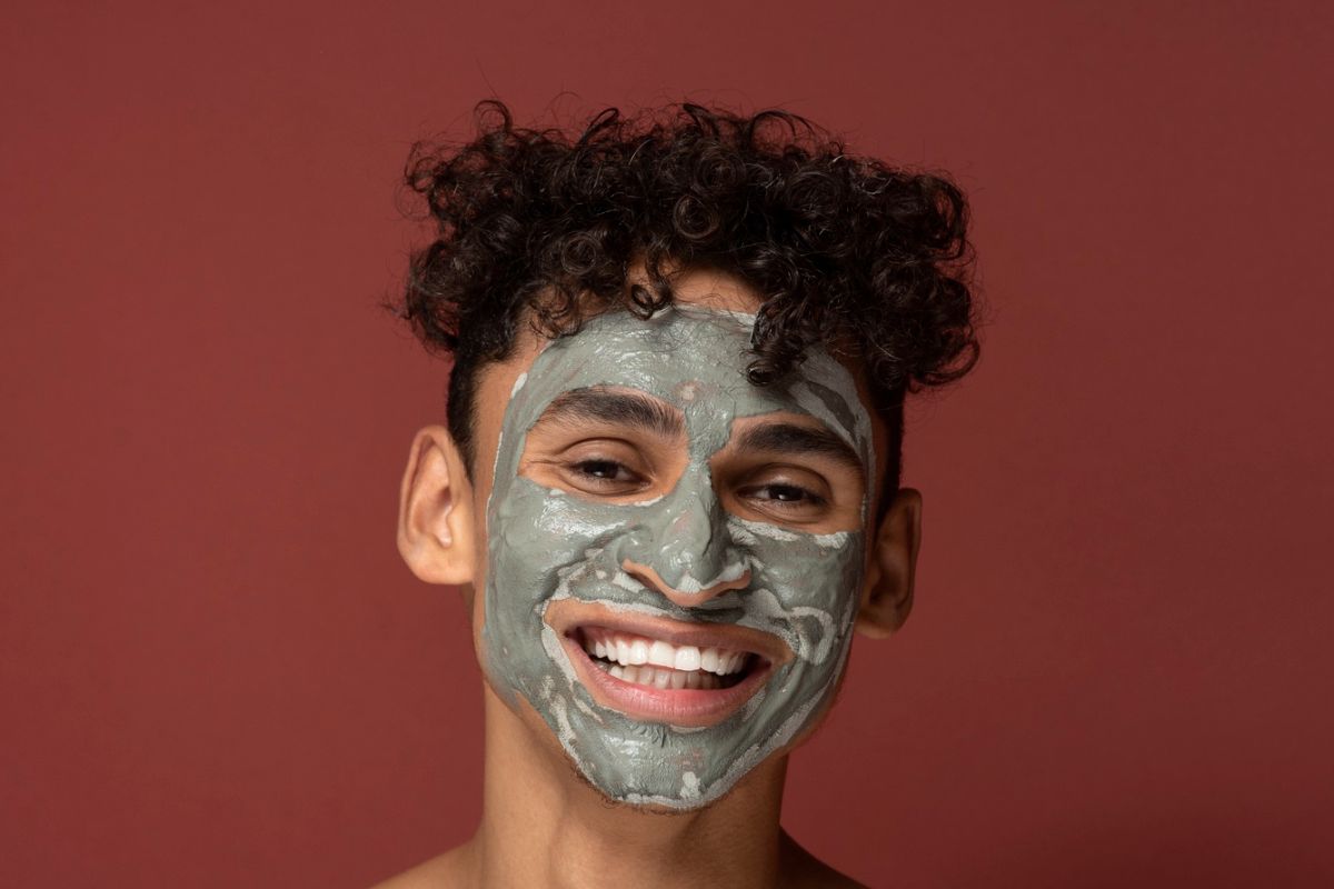 pria rambut keriting memakai masker sambil tertawa