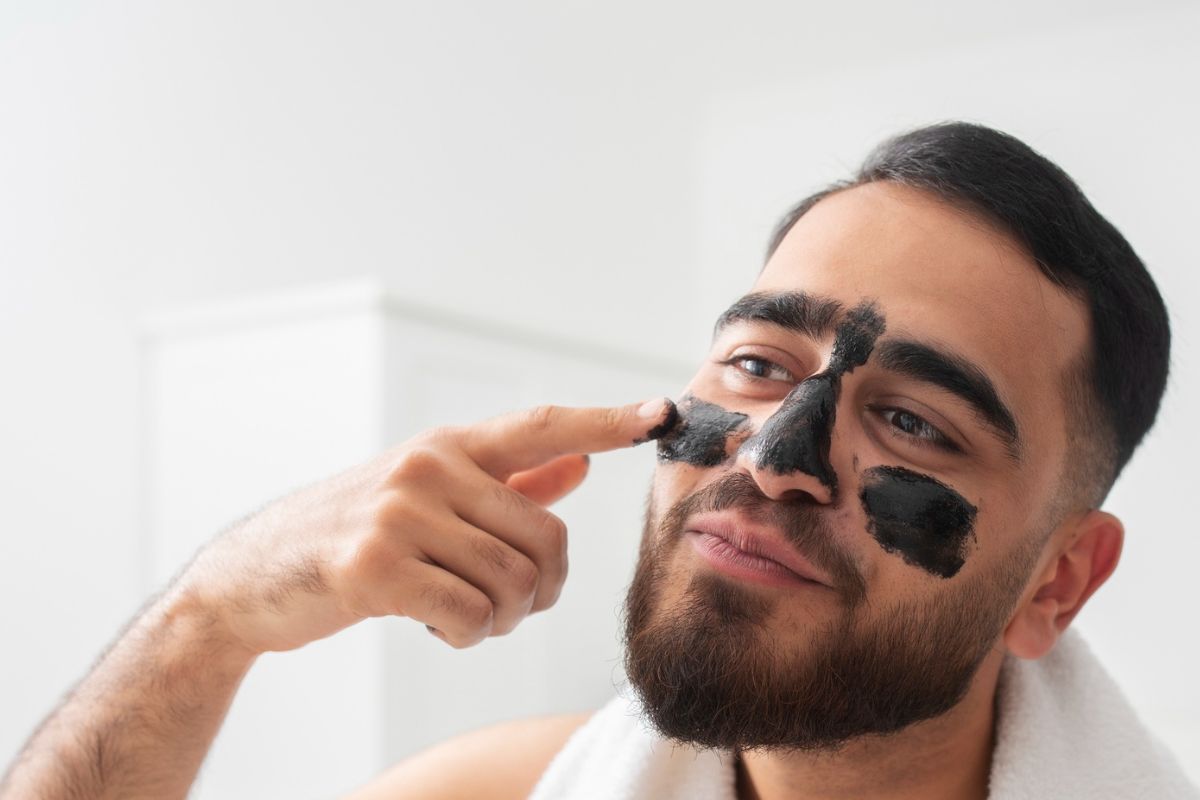 pria sedang memakai masker charcoal di wajahnya