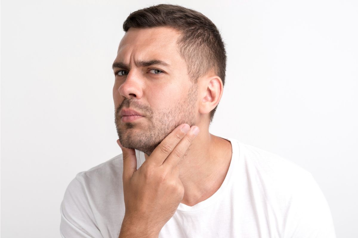 seorang pria sedang memperhatikan wajahnya di cermin