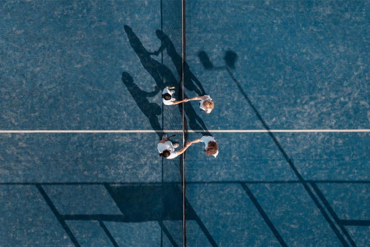 empat pemain saling berjabat tangan di lapangan padel