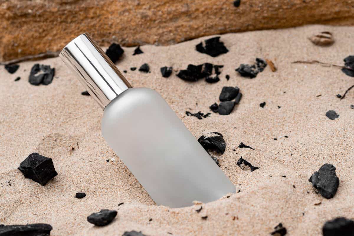 botol parfum di atas pasir putih
