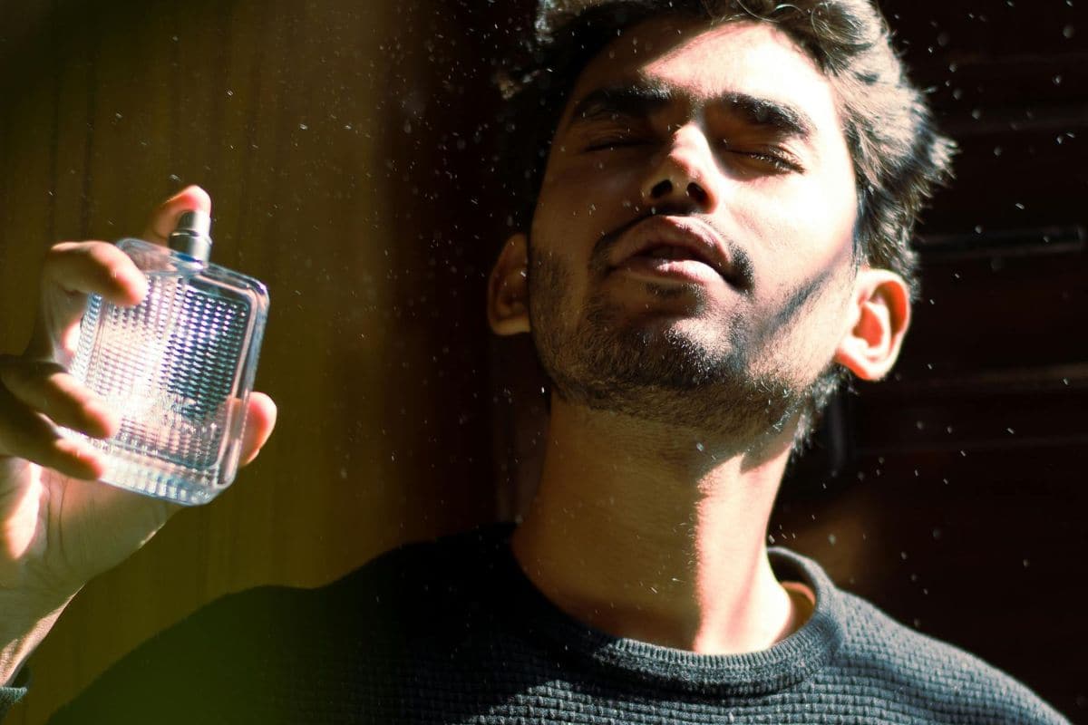 pria sedang menyemprotkan parfum