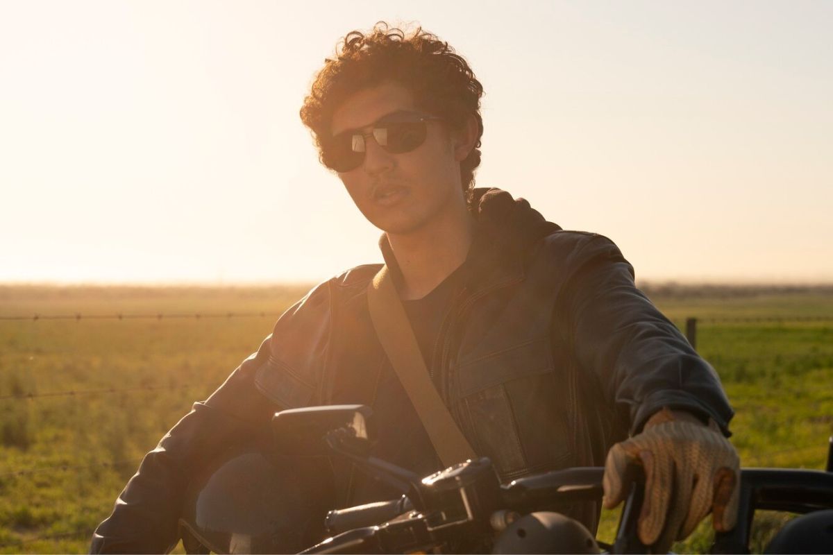 Pria duduk di atas motornya di bawah sinar matahari