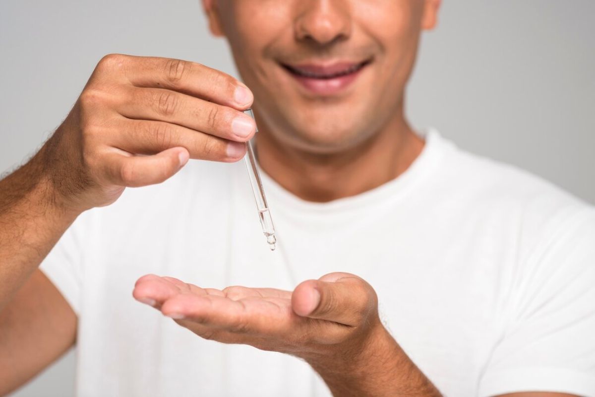 Pria menuangkan serum di telapak tangannya