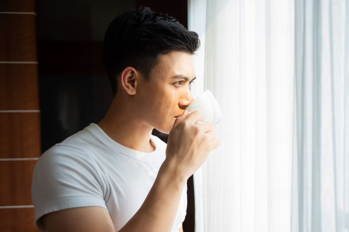 Pria sedang minum air mineral.