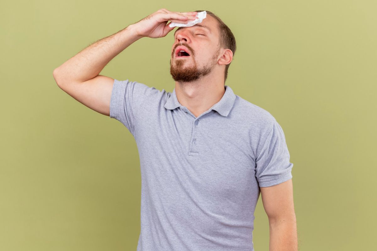 pria kepanasan dan menyeka keringat di dahi