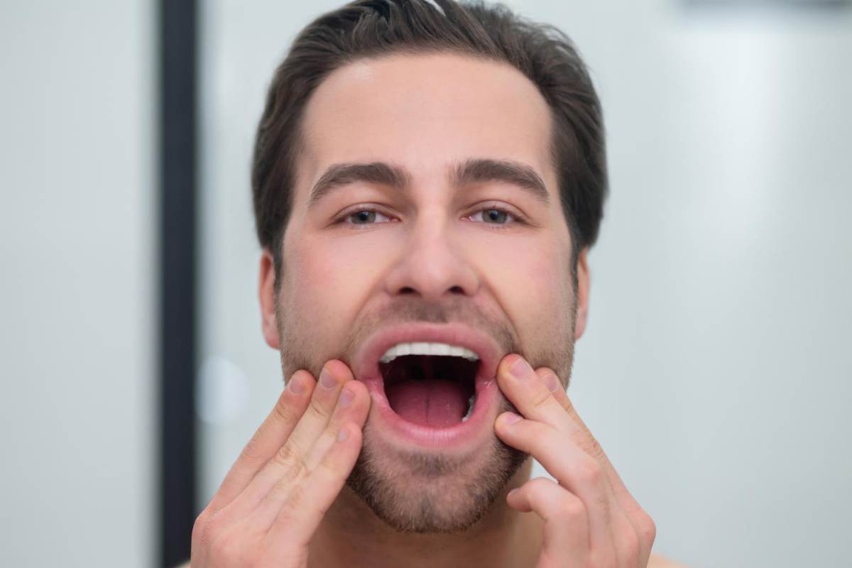 pria memegang mulut yang terbuka lebar