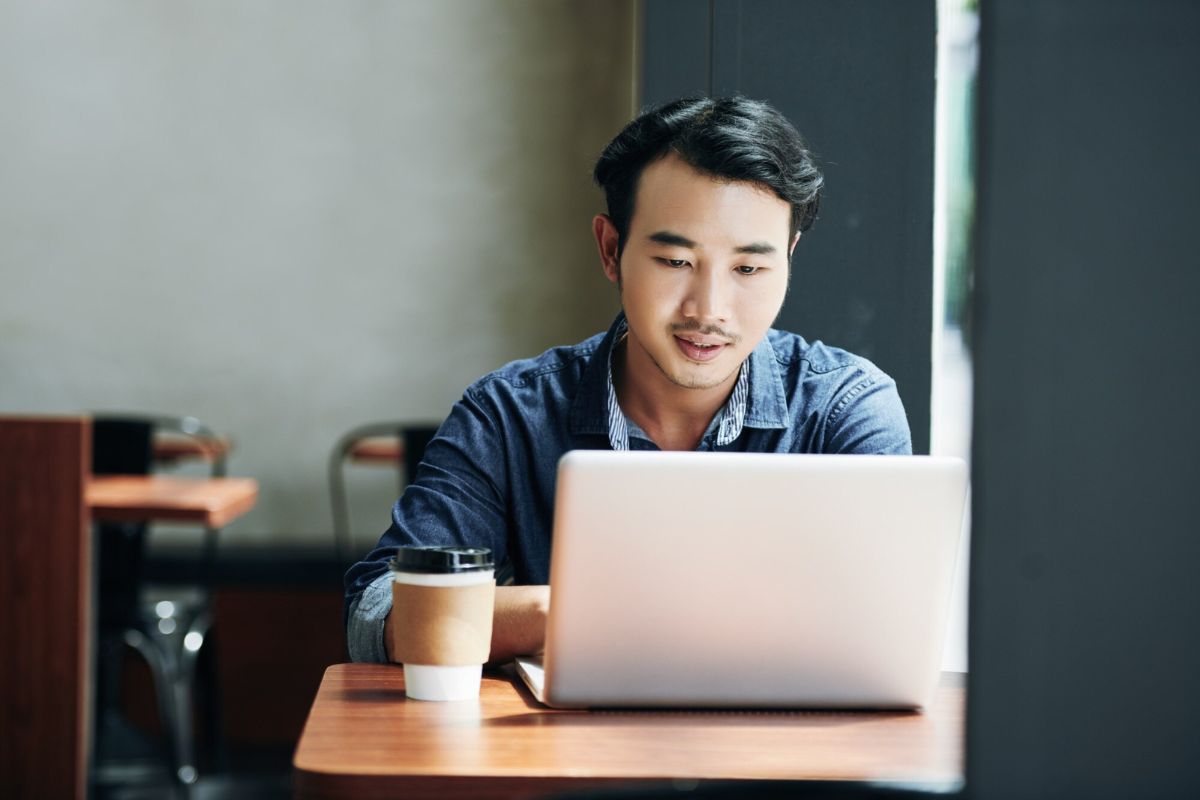 Pria menggunakan laptop di kafe
