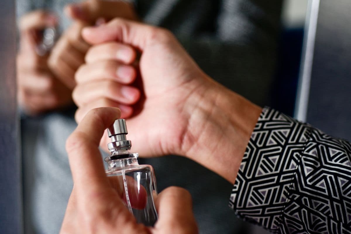 Seorang pria sedang menggunakan parfum di area pergelangan tangan
