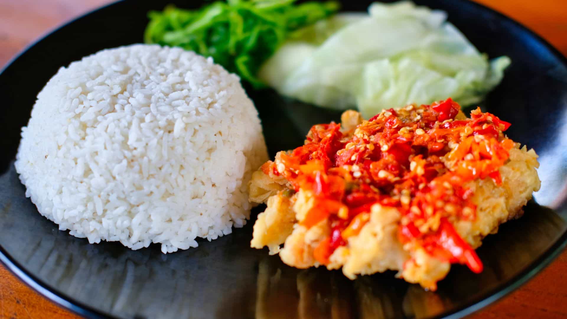 Sepiring makanan berisi nasi, lalapan kol, dan ayam geprek
