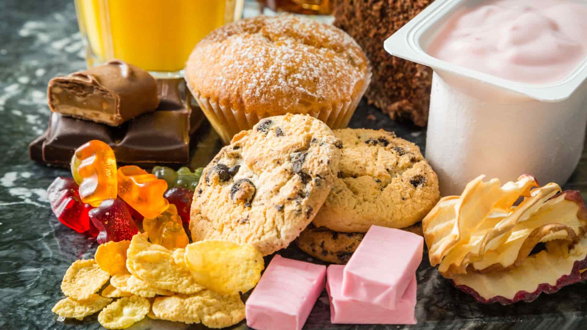 Foto berbagai makanan manis seperti permen, cookies, coklat, dan cornflake